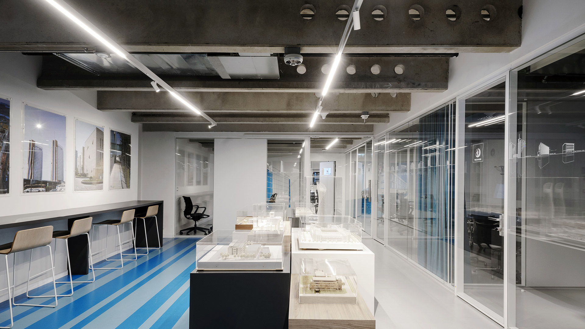 Artemide A.24 Magnetic Track: black horizontal rail with six adjustable cylindrical black spotlights, suspended by a single cable