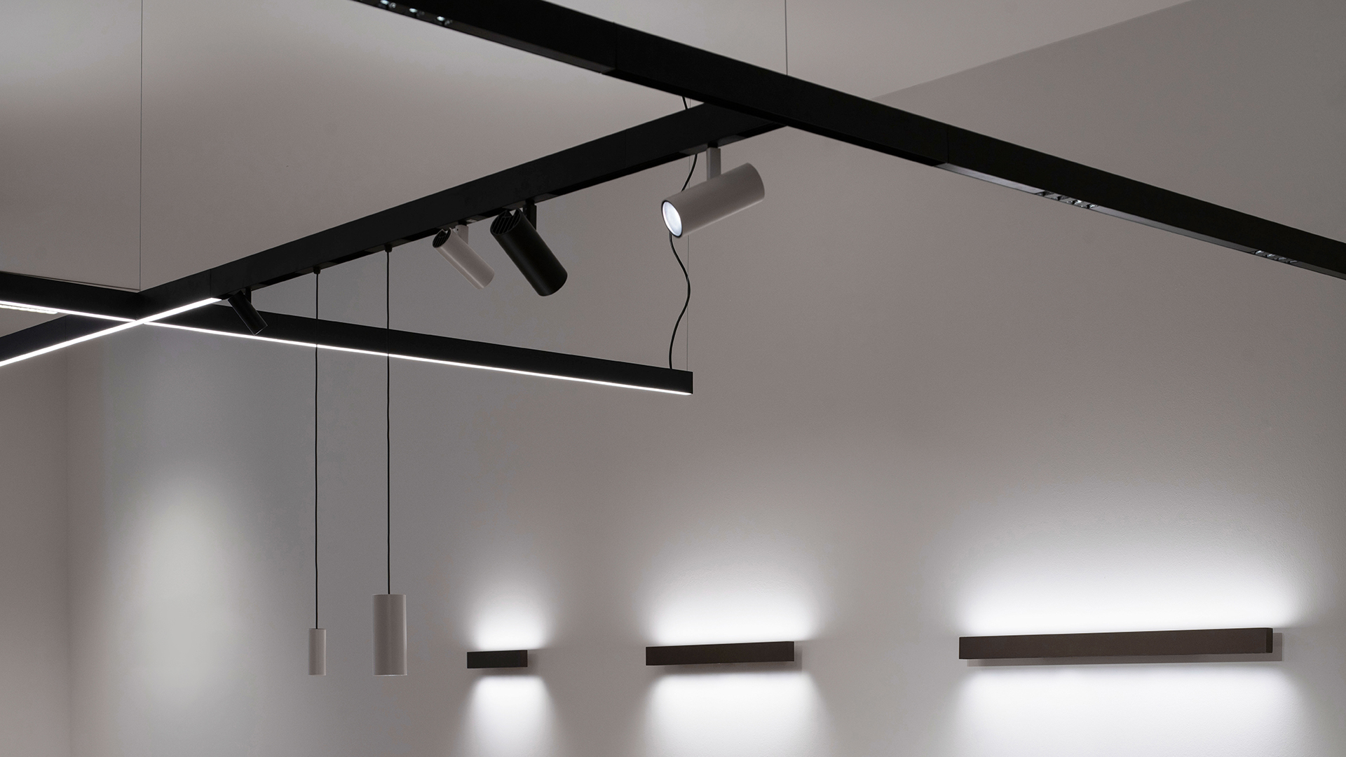 Artemide A.24 system: ceiling recessed spotlights on track and a continuous linear LED light strip mounted on a grey wall.