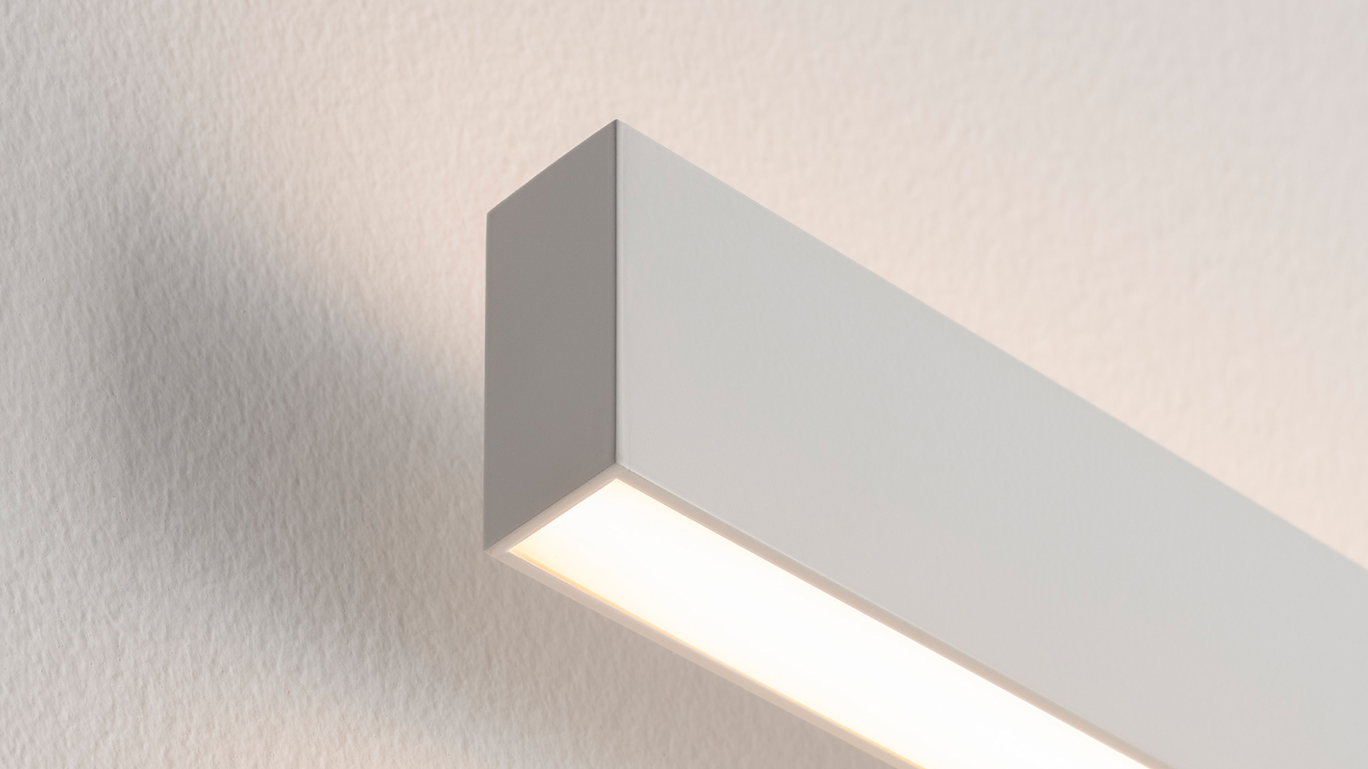 Artemide A.24 Parete wall lamp: sleek white rectangular LED linear fixture mounted on wall, emitting warm diffused light