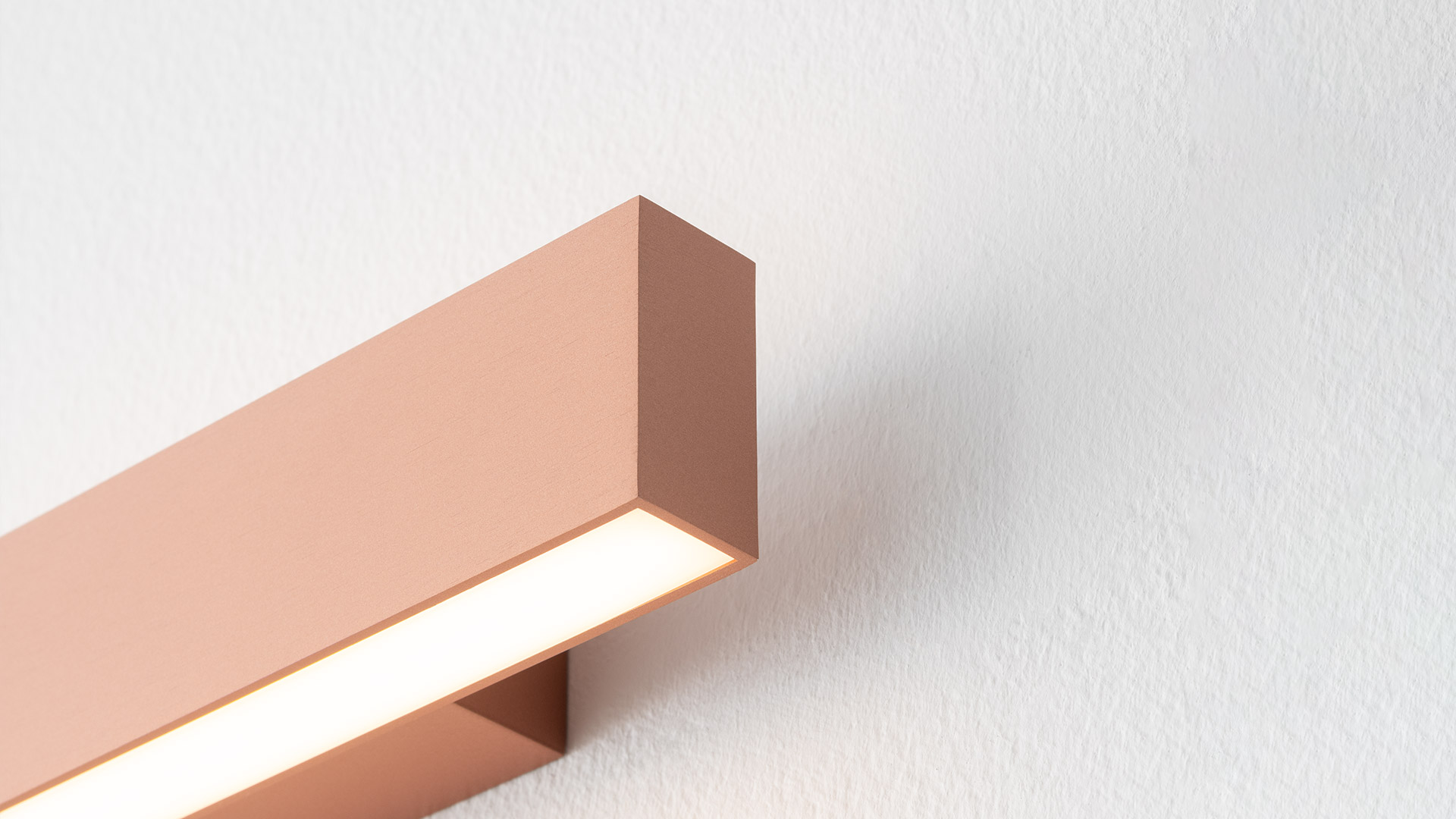 Three Artemide A.24 Parete wall lights mounted at different heights, emitting soft horizontal light bands on white walls.