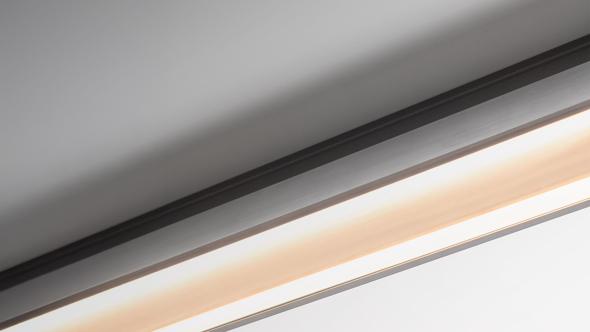 Artemide A.24 Wall Washer linear LED ceiling fixture emitting warm white light along a sleek dark aluminum profile