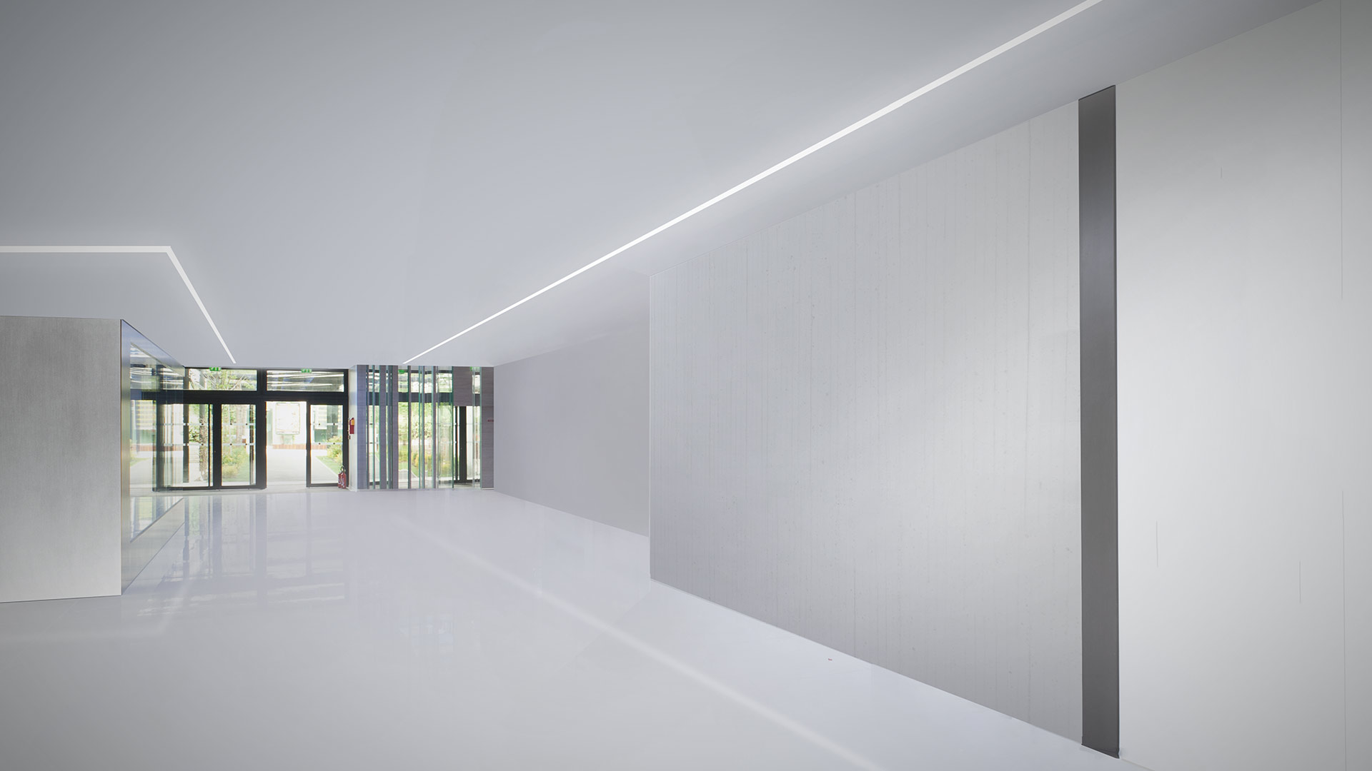 Modern office interior with Artemide A.39 recessed linear LED lights on ceiling and walls, blue storage units, and colorful ottomans