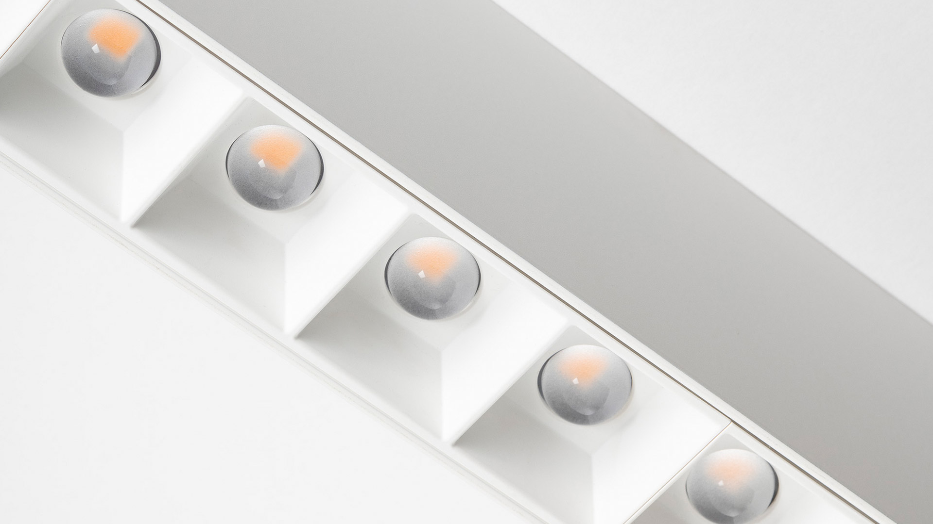 Modern showroom with Artemide A.39 recessed ceiling lights and linear LED strips illuminating dark display pedestals on curved floor
