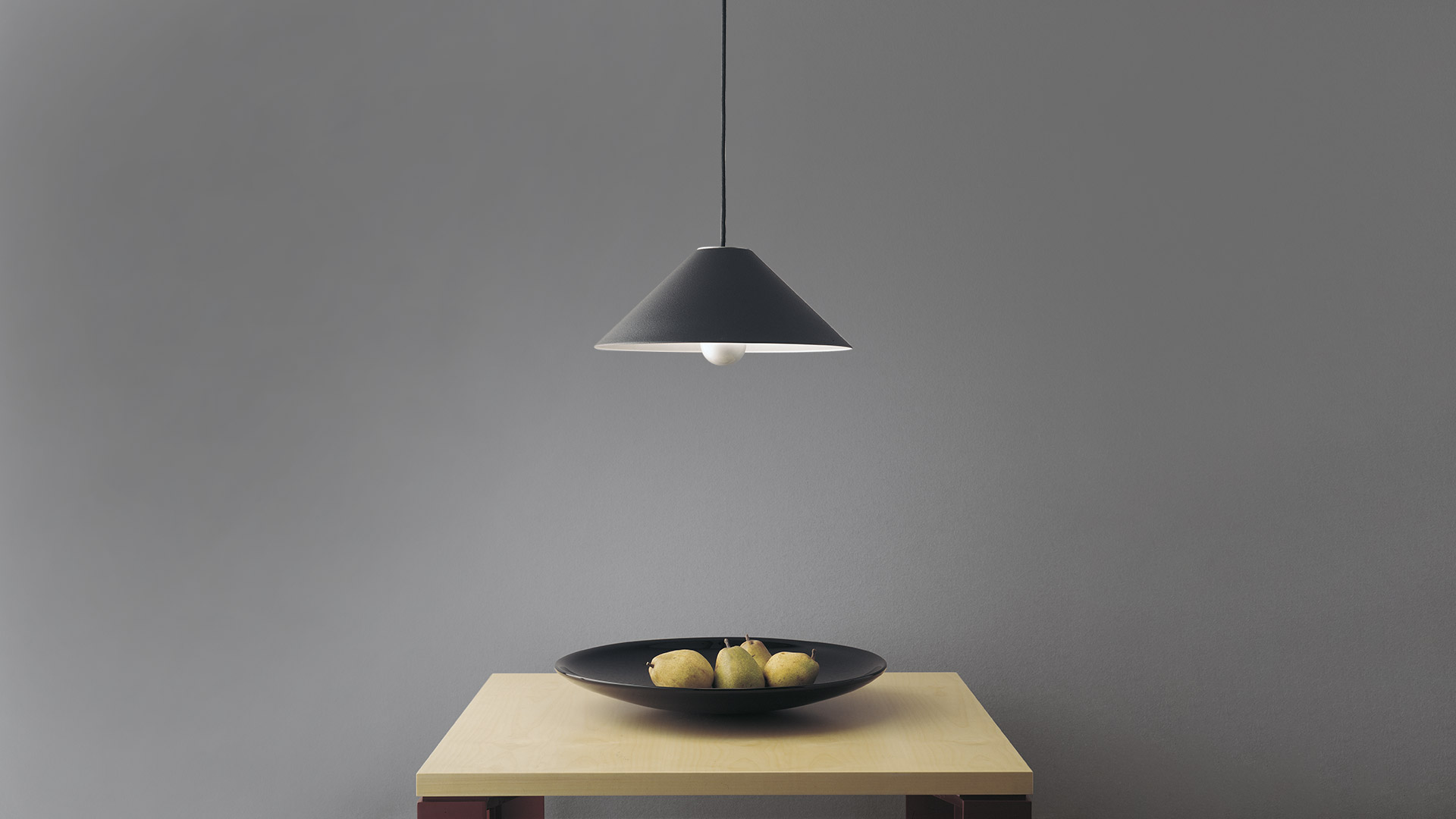 Two Artemide Aggregato pendant lamps: left spherical white glass globe, right conical dark shade with pulley mechanism on black cords