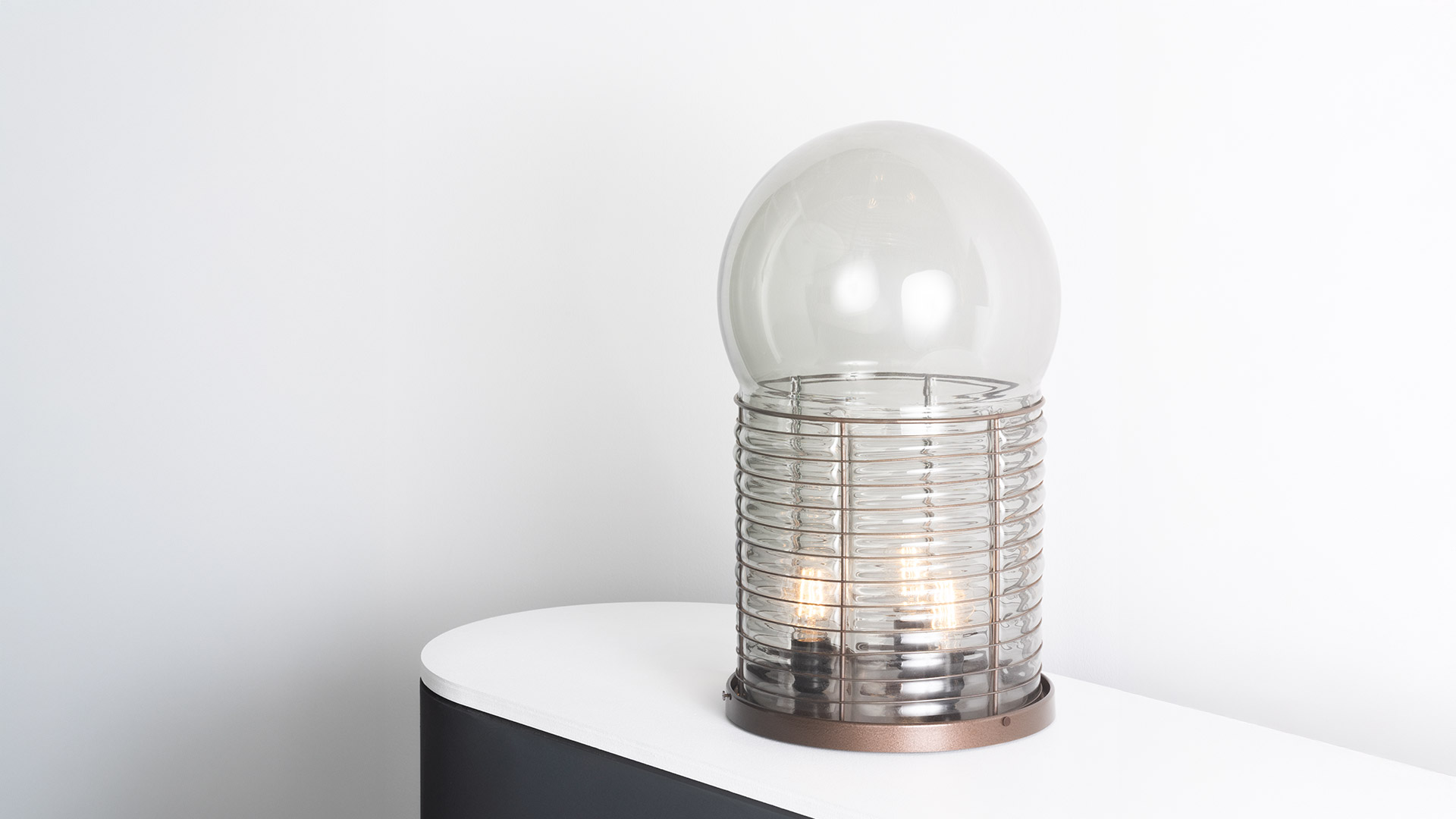 Two close-up views of Artemide Alcinoo lamp: left chrome ribbed metal cage with globe bulb, right copper base with ribbed glass diffuser