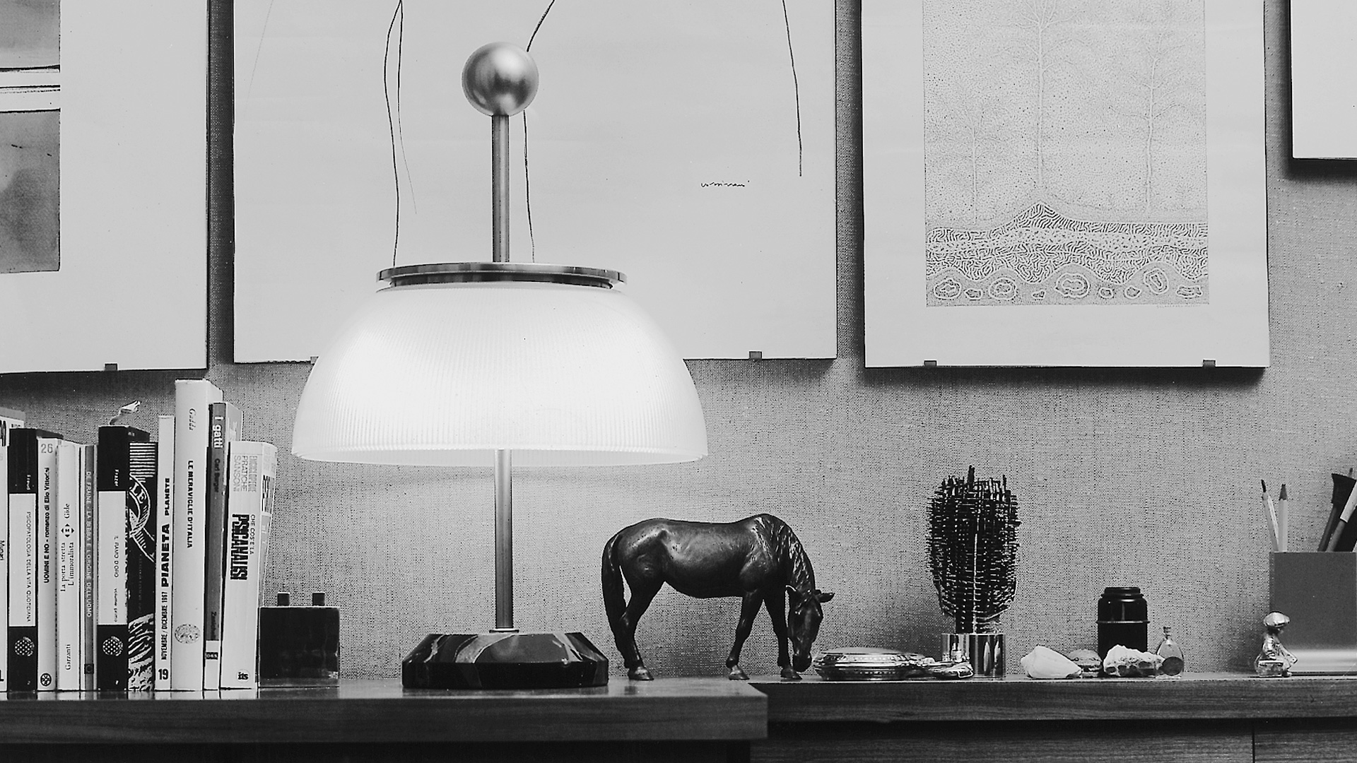 Artemide Alfa table lamp with opal glass dome shade and dark metal structure, casting warm ambient light on a wooden bedside table