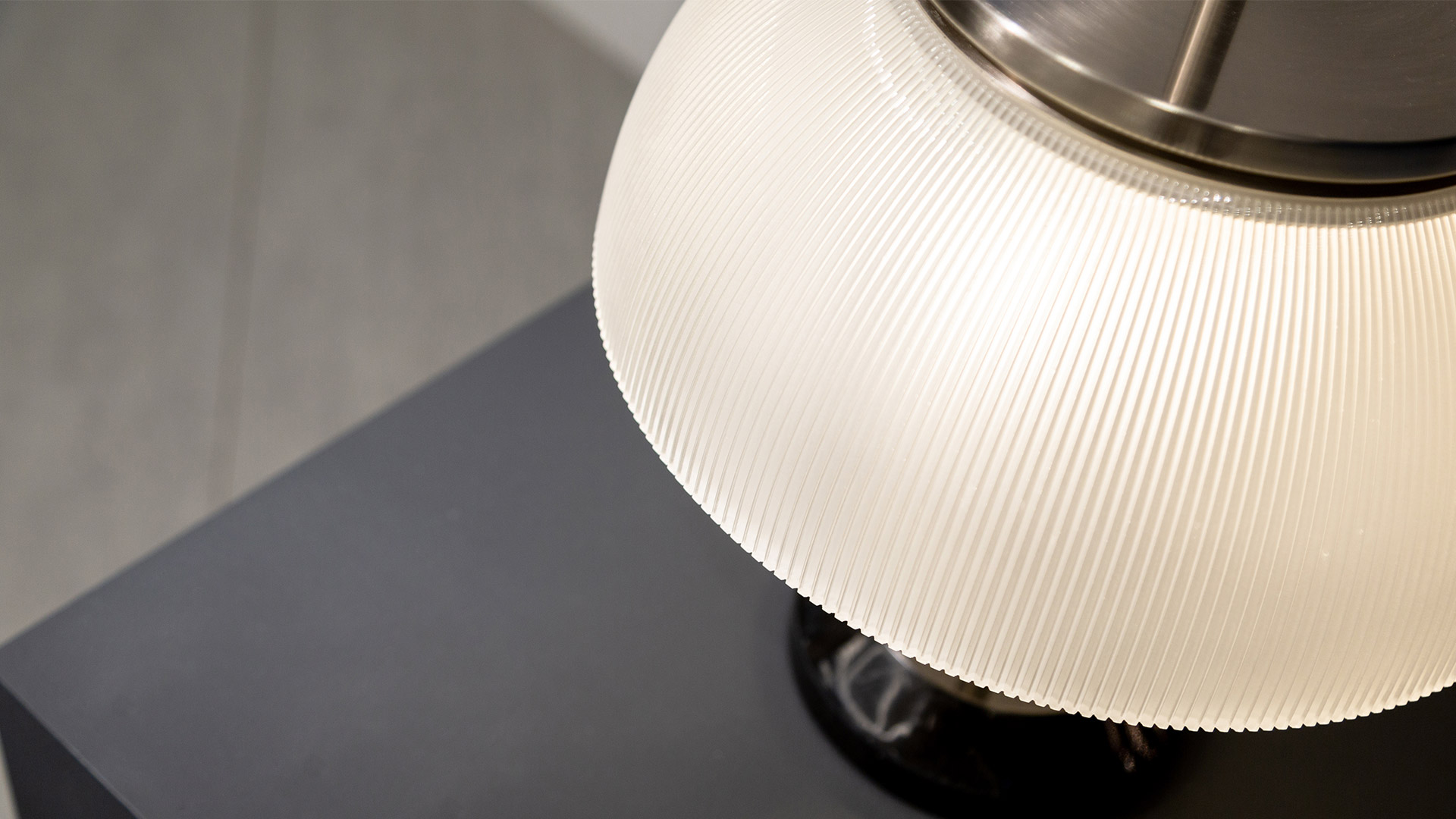 Artemide Alfa table lamp with dome-shaped diffuser, black stem and spherical finial, shown in two color variants on red background