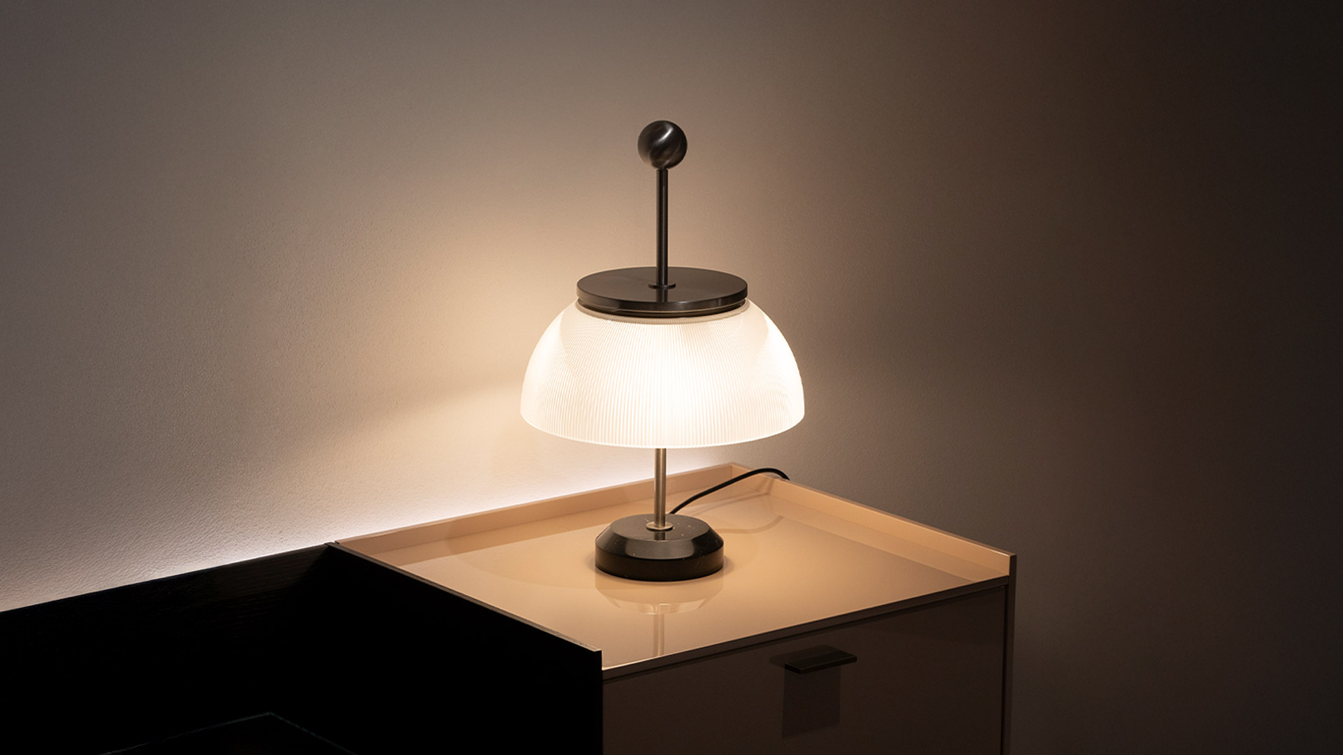 Artemide Alfa table lamp with ribbed opal glass dome shade and polished metal top detail on dark base