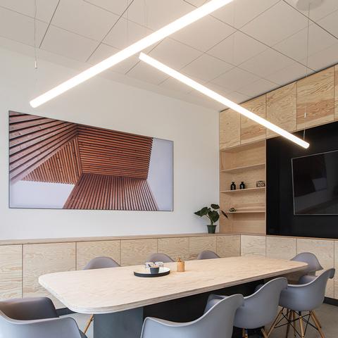 Artemide Alphabet of Light Linear pendant lamps arranged diagonally above a conference table in a modern meeting room