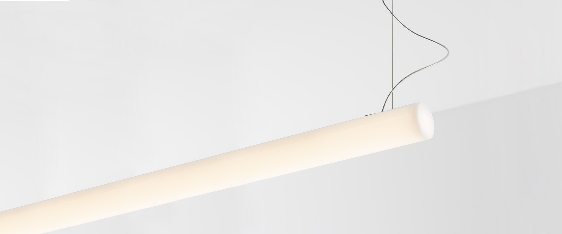 Modern meeting room with Artemide Alphabet of Light Linear suspended fixture forming an L-shape over a light wood conference table with grey chairs