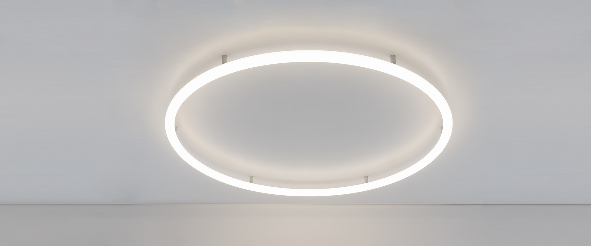 Modern office with Artemide Alphabet of Light Circular pendant lamps illuminating a meeting area with black chairs and white table