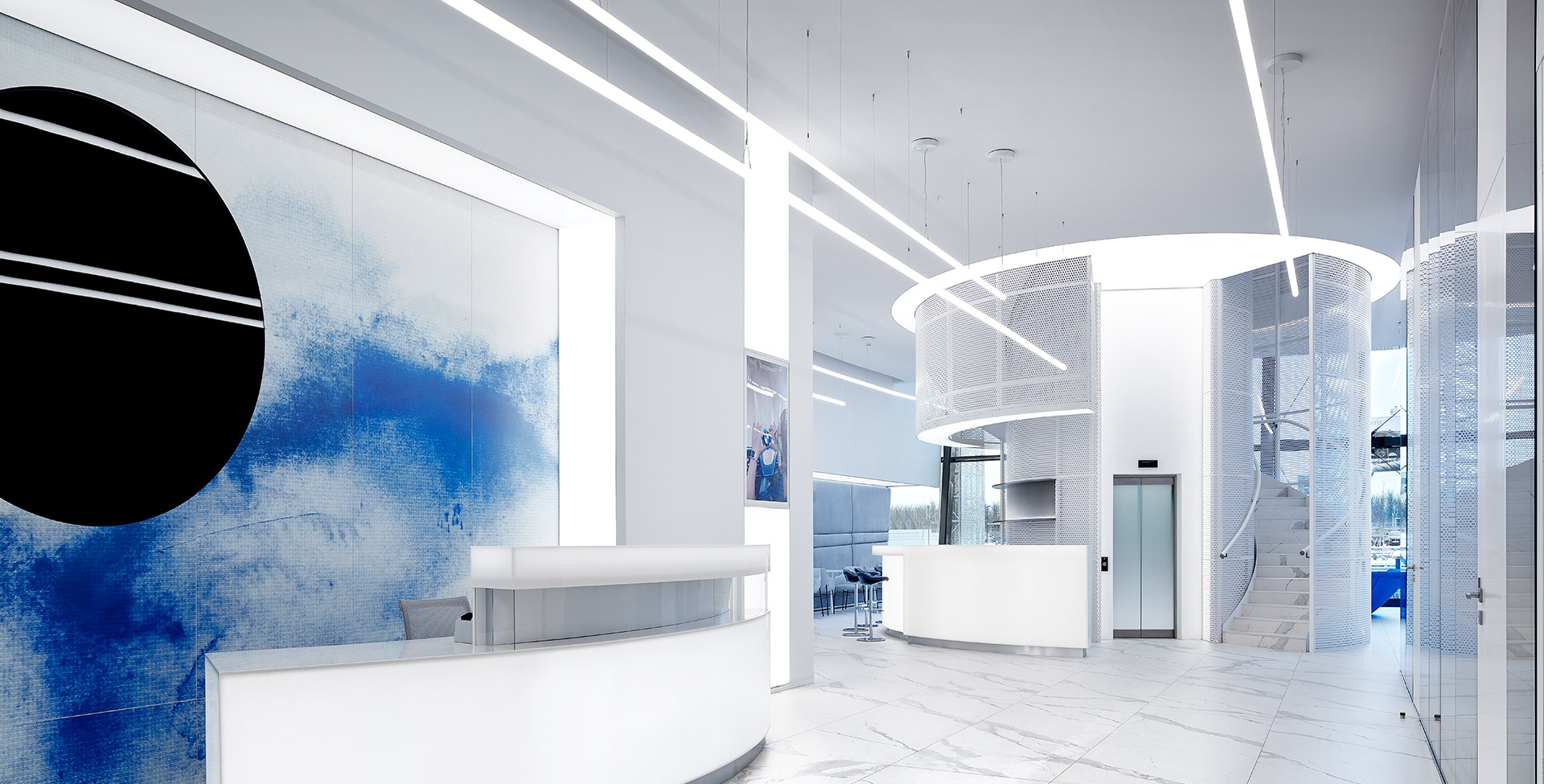 Modern lounge with Artemide Alphabet of Light System on wood ceiling, black armchairs, magazine shelves, and dining area with city view