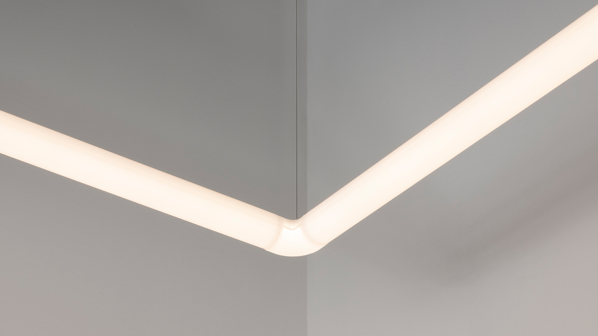Artemide Alphabet of Light installation: white LED linear modules forming letters on blue and white geometric walls with wood floor