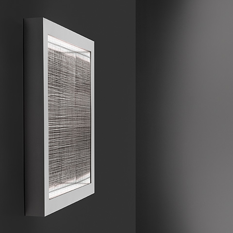 Artemide Altrove wall/ceiling lamp with white rectangular frame and woven textile diffuser emitting soft indirect light, mounted on dark wall