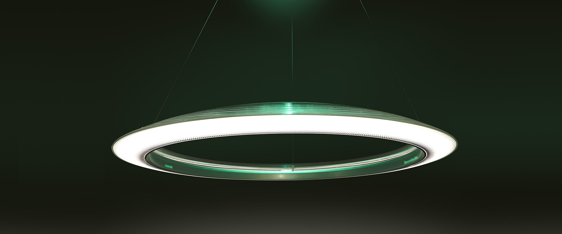 Artemide Ameluna pendant lamp: circular LED ring with white and green glow, suspended by cables against a dark green background