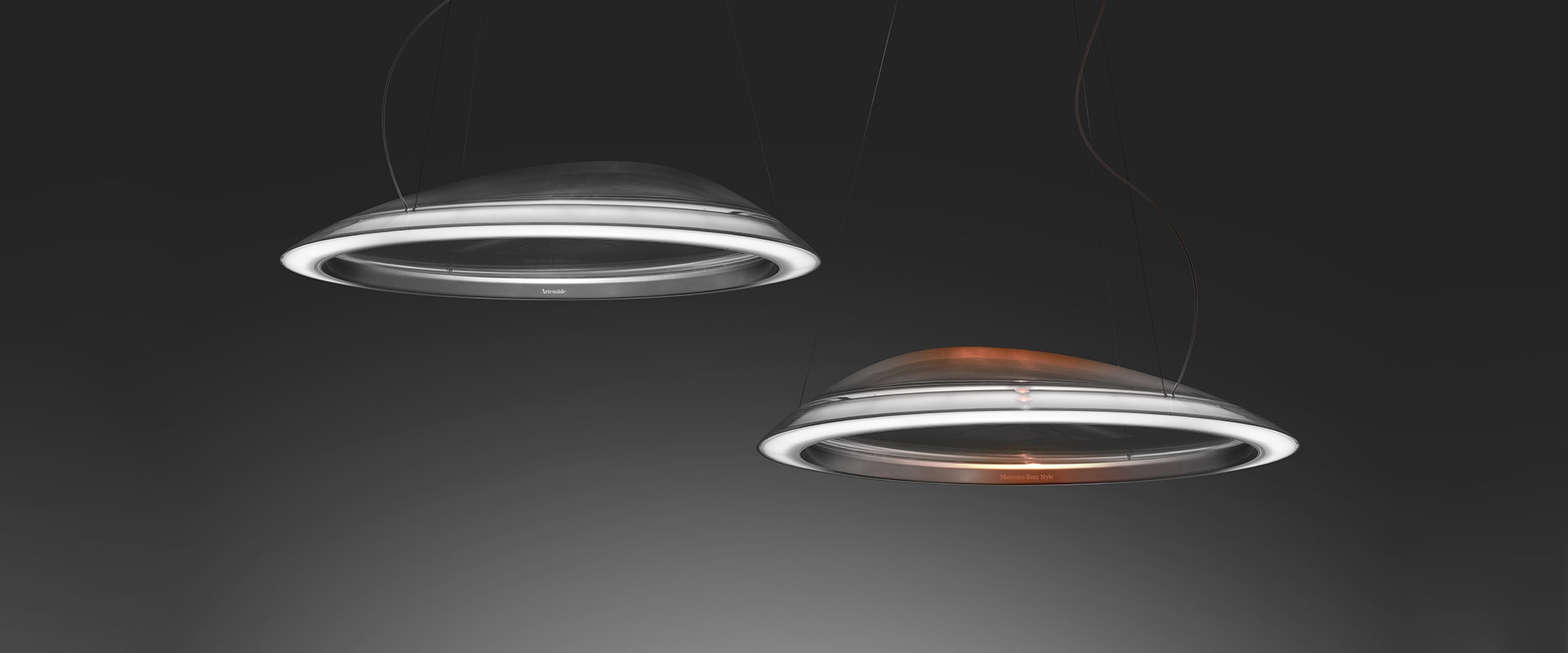 Two Artemide Ameluna pendant lamps with circular LED rings, one silver finish and one with warm copper interior, on dark background