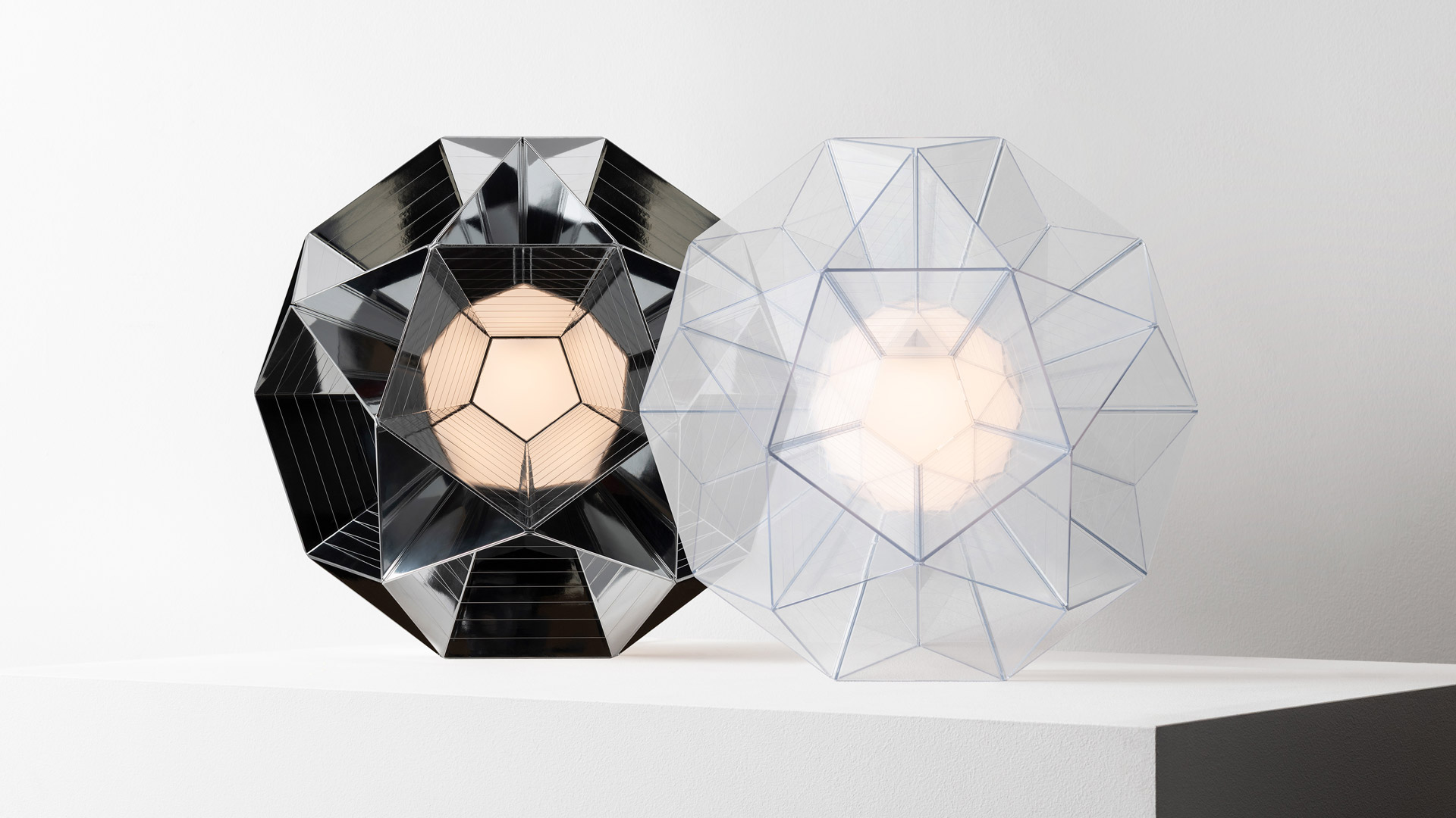 Artemide Arctic lamp with faceted crystal-like geometric body glowing at sunset, reflected on a mirror surface against a vivid sky
