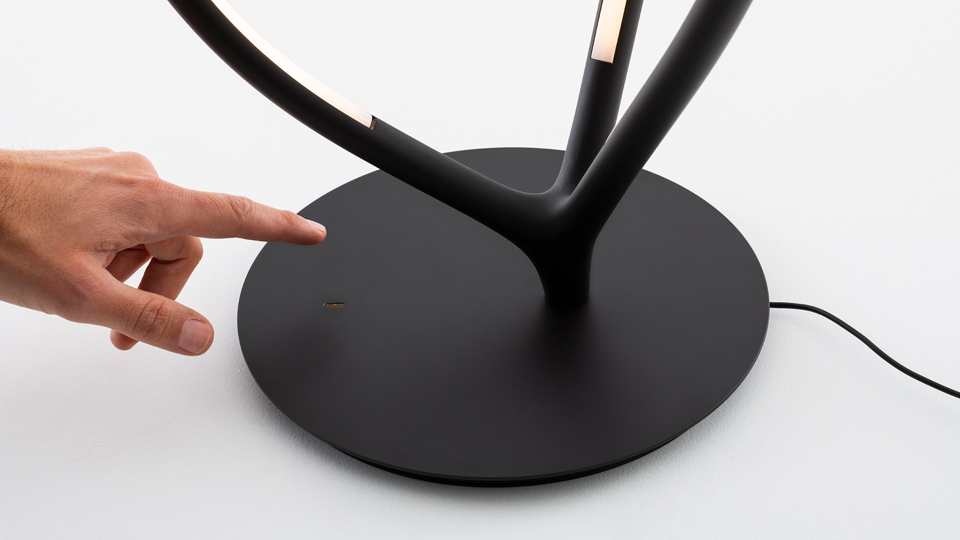 Two Artemide Arrival table lamps: left teardrop-shaped gold frame, right black frame with integrated LED strip, on round bases