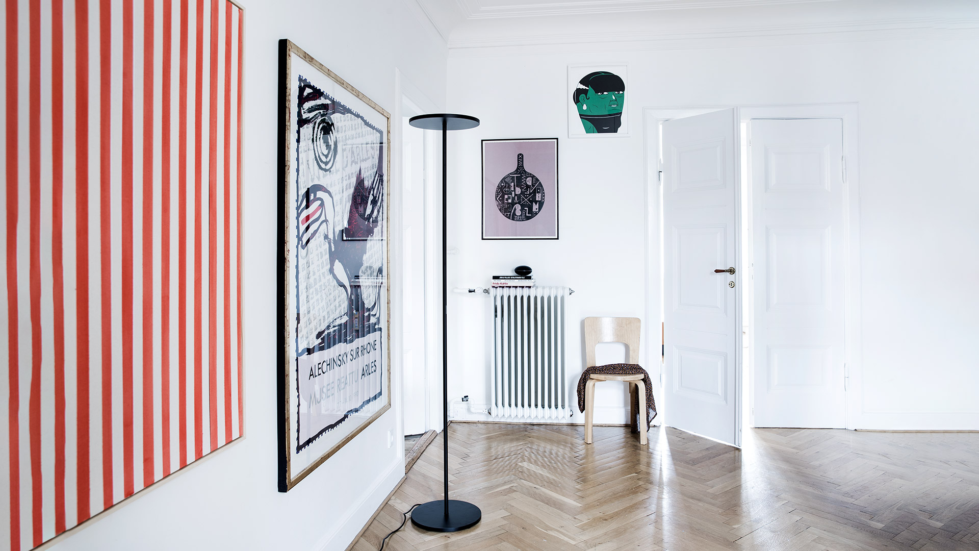 Athena floor lamp by Artemide: slim black stem with circular disc diffuser, shown full view and close-up detail of the flat round shade