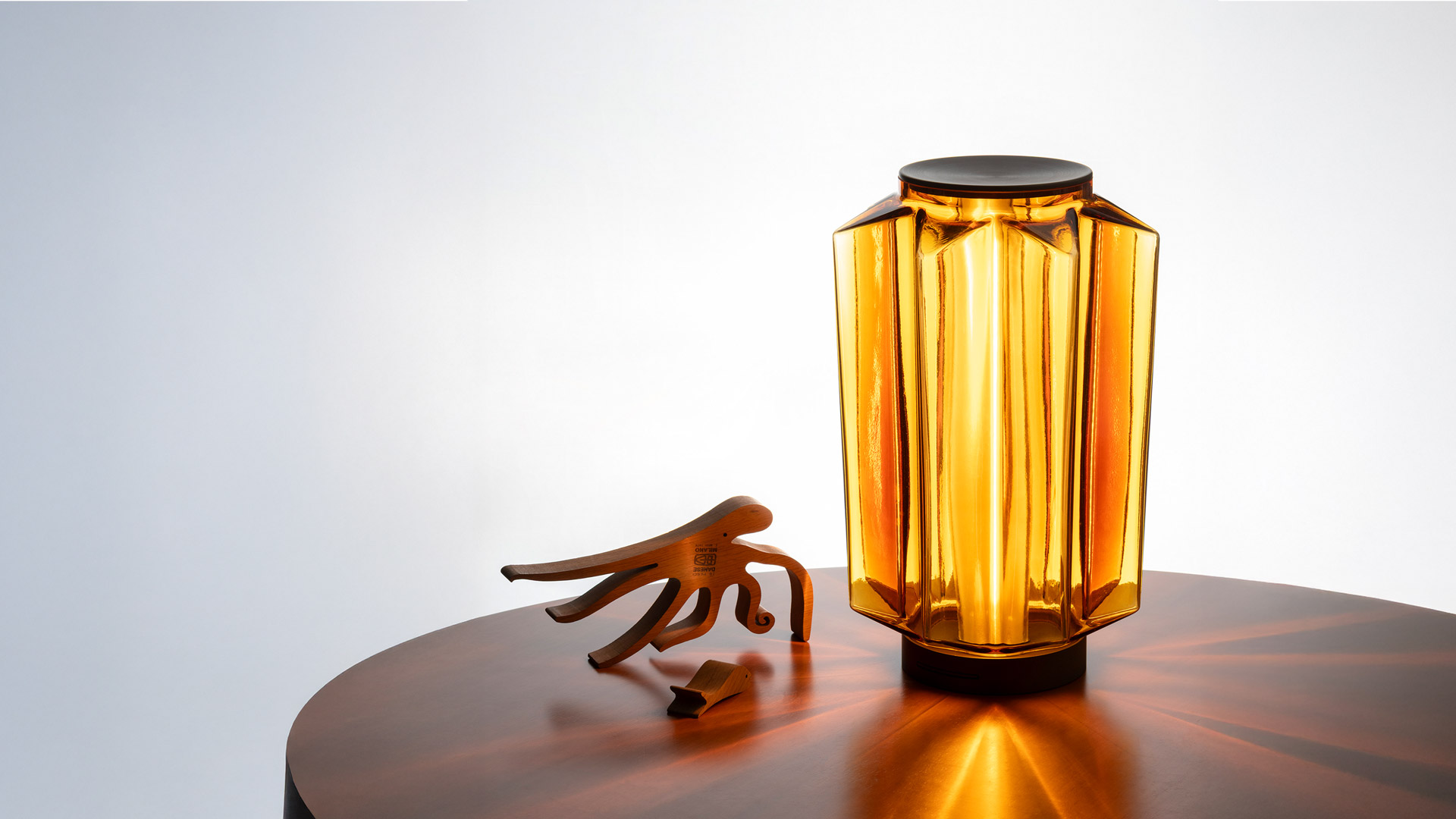 Artemide Auralia lamps: two amber glass table lamps and one pendant, featuring faceted cylindrical shades with warm golden glow
