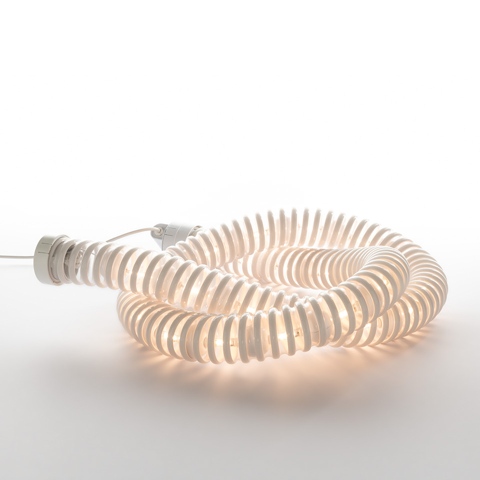 Artemide Boalum lamp: flexible luminous white tube coiled in a spiral on a surface, emitting warm diffused light