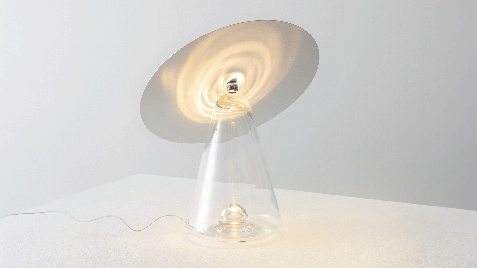 Boltons table lamp with conical glass shade and warm glow on a wooden sideboard, beside a leather armchair against a deep blue wall