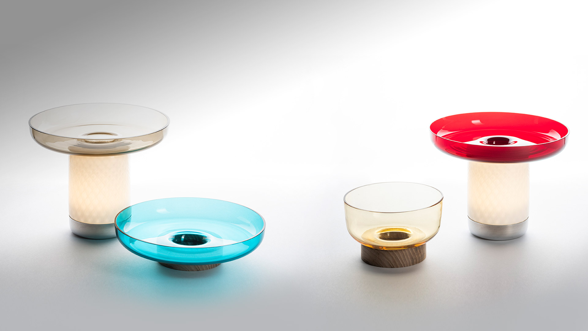 Chef holding an Artemide Bontà portable lamp glowing warm white light in one hand and a dish ingredient in the other