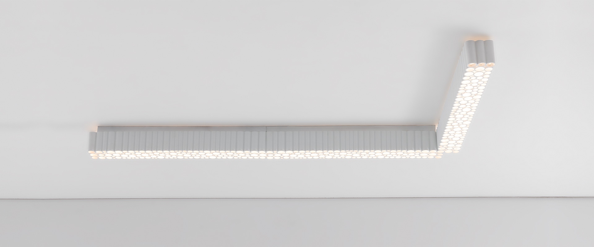 Artemide Calipso Linear System: L-shaped ceiling light with textured LED diffuser panel in white, mounted flush to ceiling