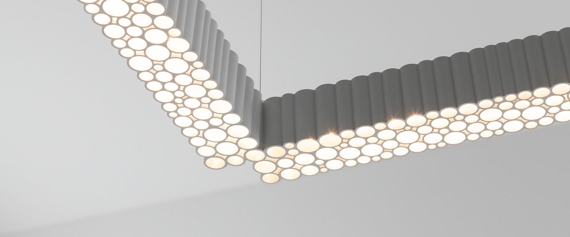 Artemide Calipso Linear System pendant lamp: sleek horizontal grey bar with textured LED diffuser, suspended by a single cable