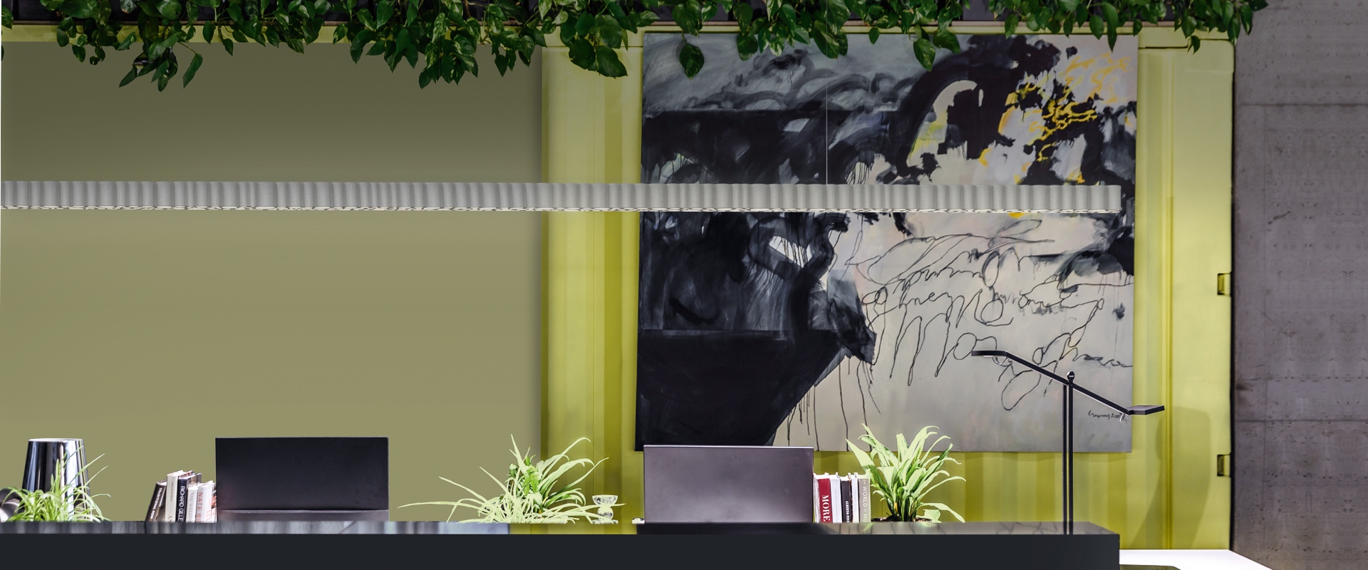 Modern reception desk with Artemide Calipso Linear System ceiling lamp, green plants, abstract artwork, and yellow accents on sage walls