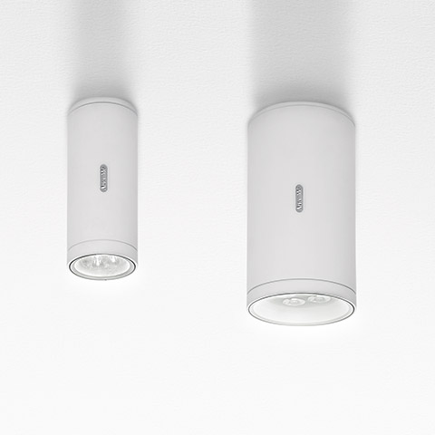 Two Artemide Calumet ceiling spotlights in white, cylindrical surface-mounted design with LED light source, shown in small and large sizes