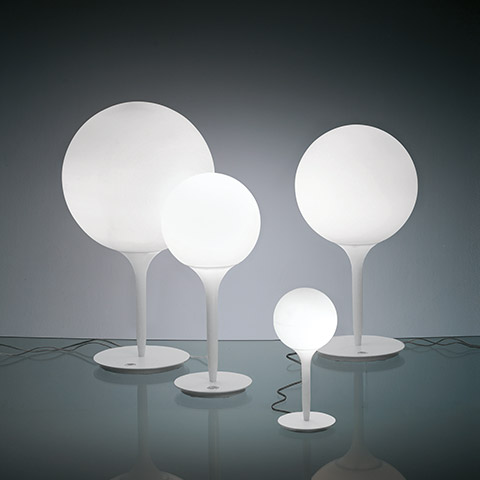 Four Artemide Castore Tavolo table lamps in varying sizes, featuring white opal glass spheres on slender white stems with round bases