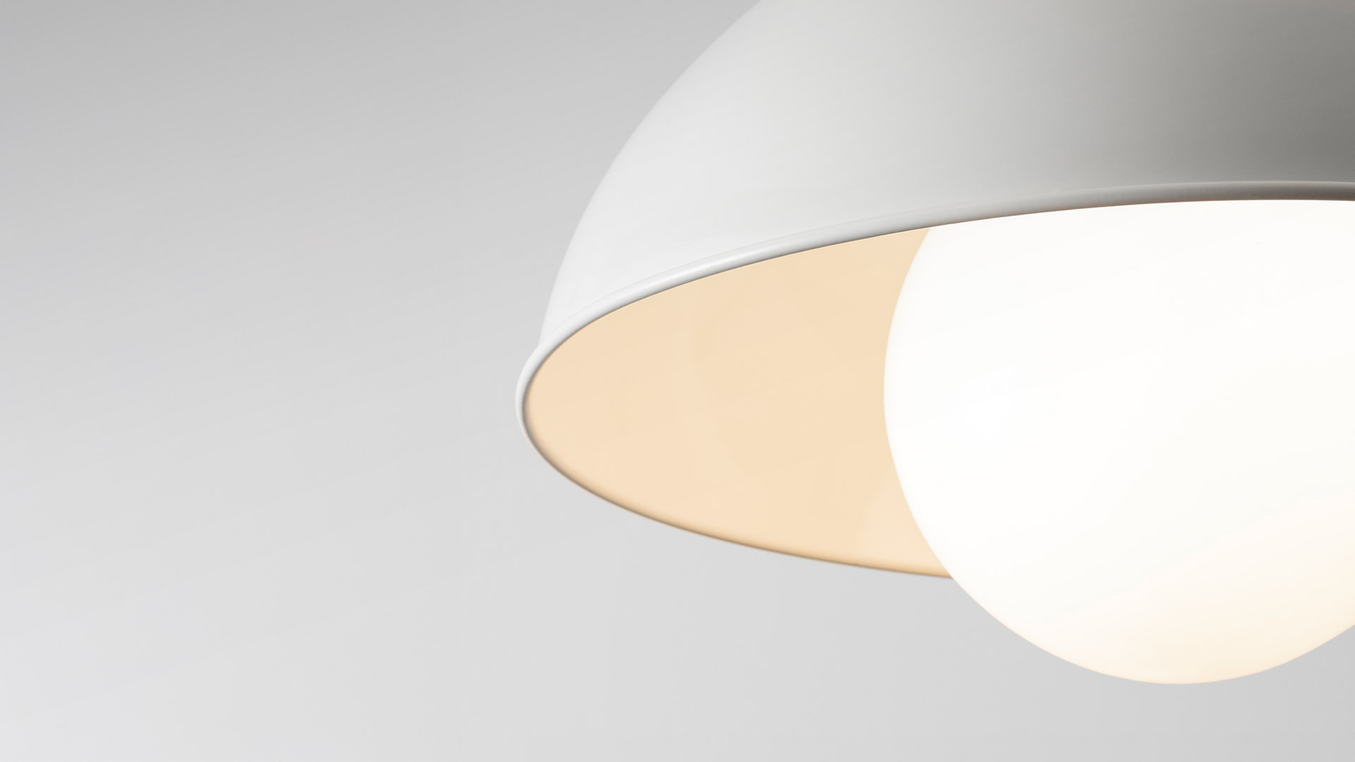 Artemide Cetra pendant lamp with white double-bowl shade and opal globe, hanging over a white table with decorative flowers.