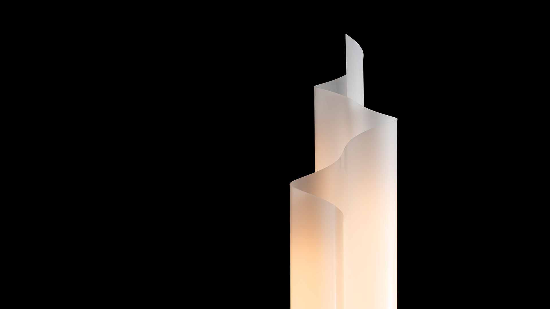 Artemide Chimera floor lamp: tall sculptural frosted white diffuser with layered vertical panels glowing warmly against black background