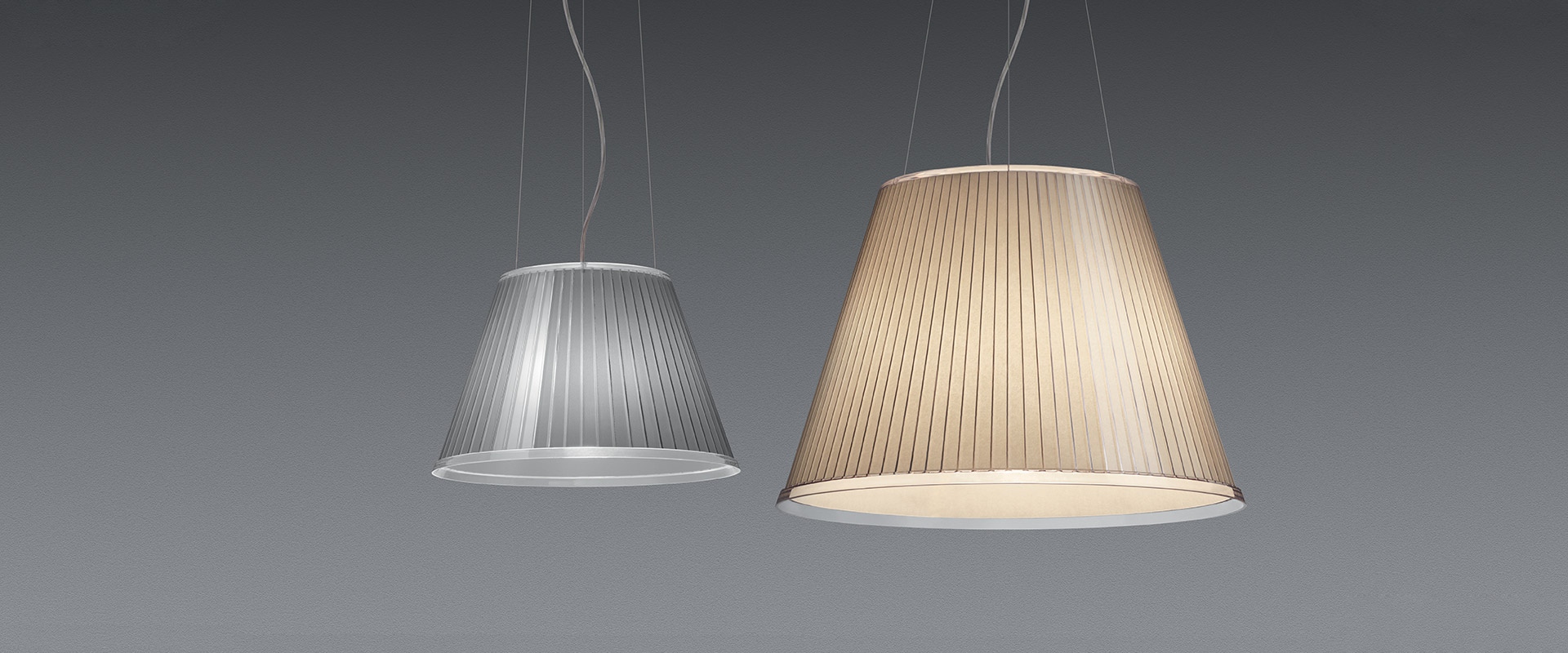 Artemide pendant lamp with conical pleated silver shade, suspended by thin cables, emitting soft diffused light from the bottom