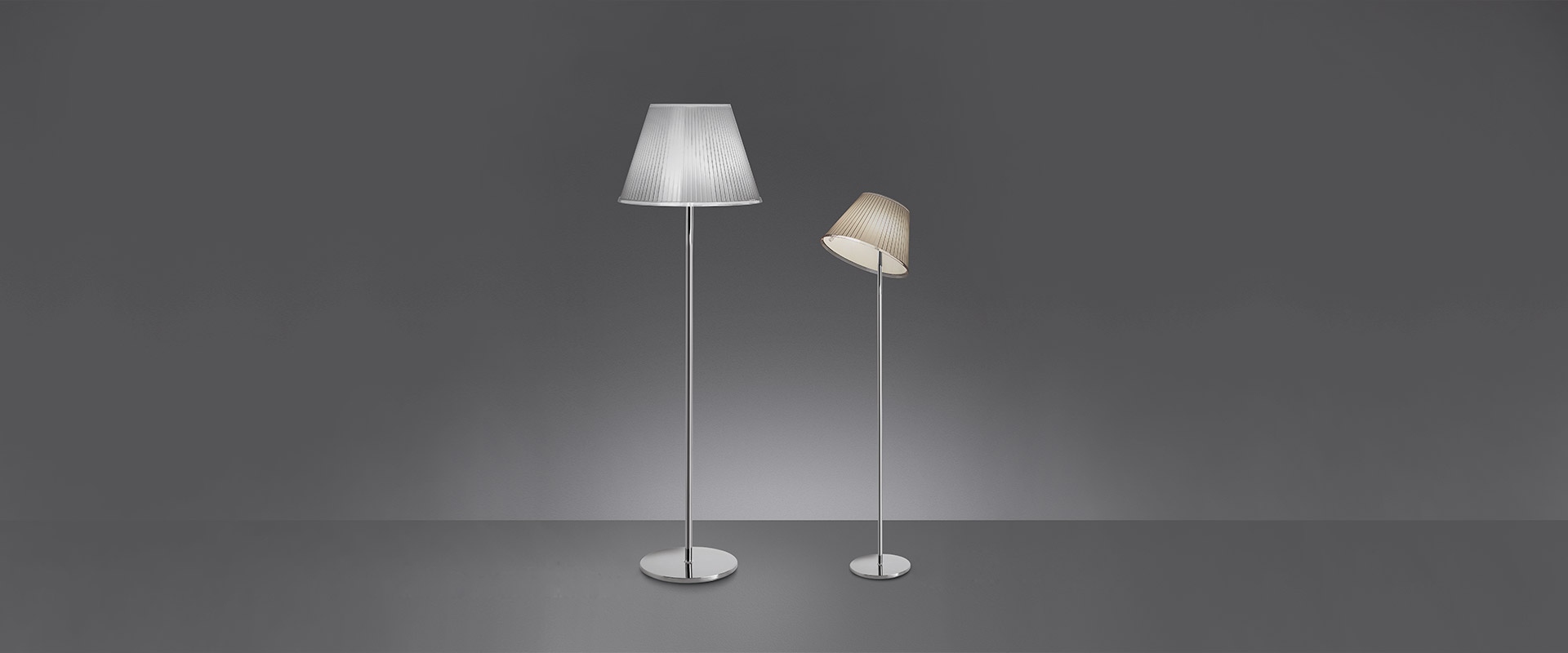 Two Artemide Choose floor lamps on chrome stems: left tall with white conical shade, right shorter with tilted beige shade
