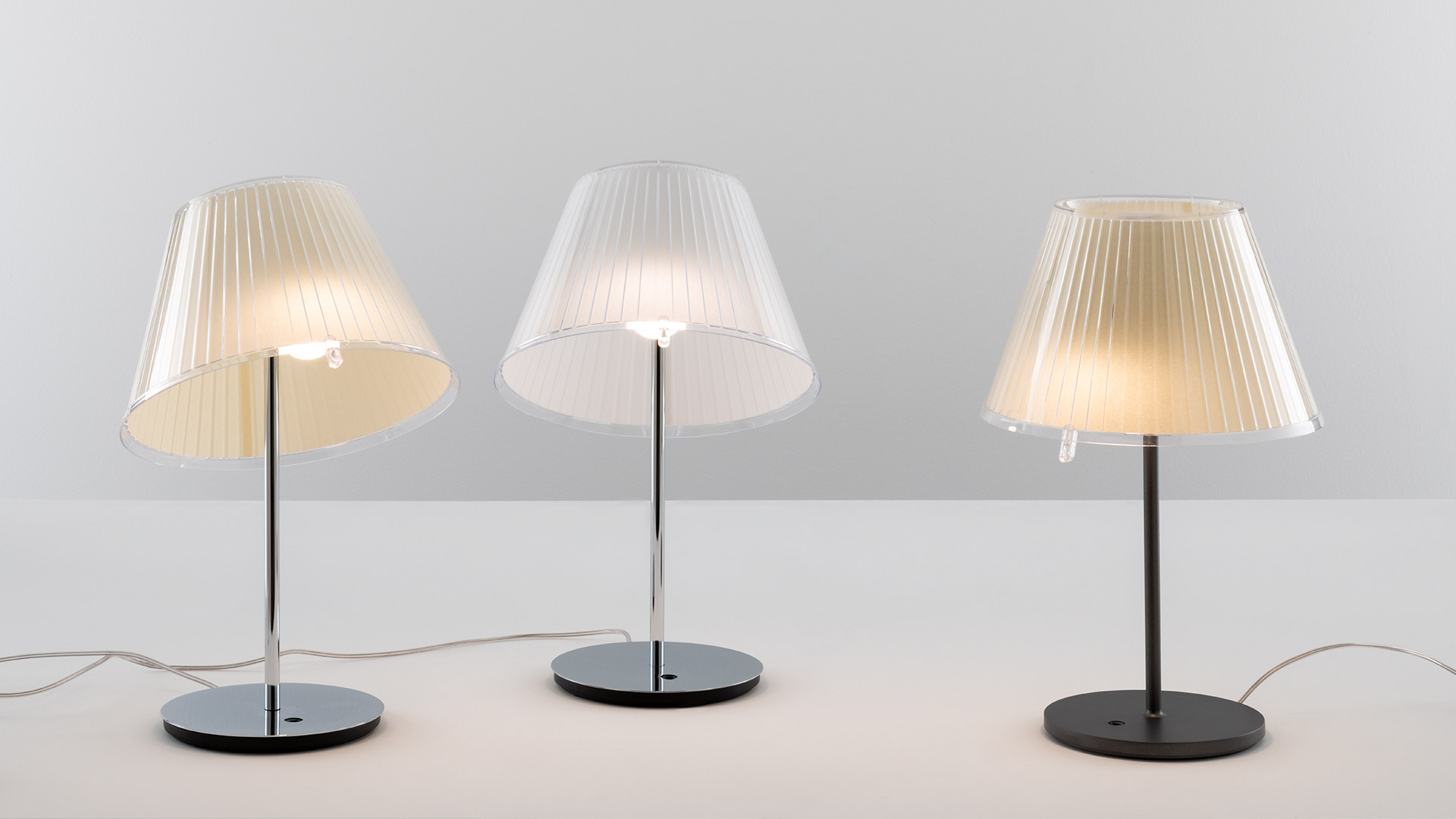 Two Artemide Choose pendant lamps: left silver pleated fabric shade, right warm beige pleated fabric shade, both conical