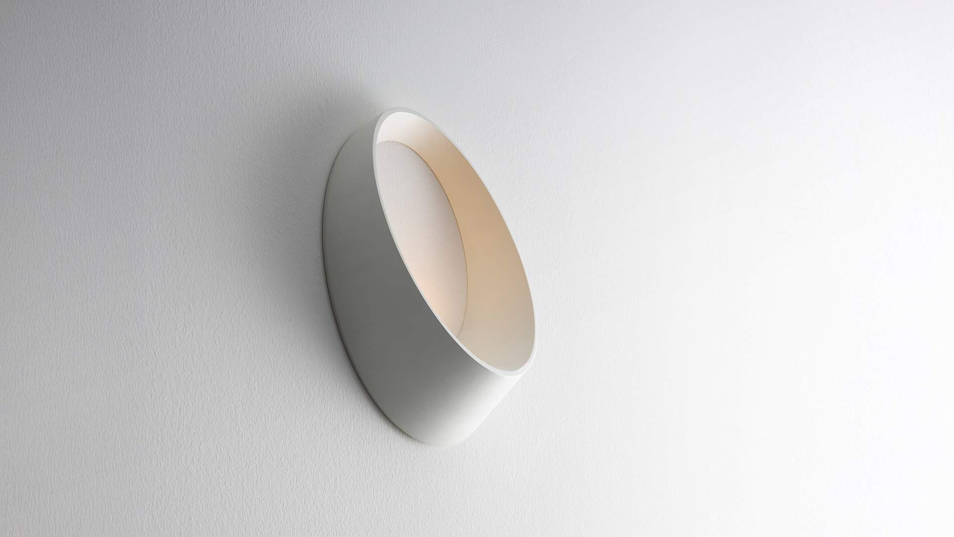 Artemide Cleomede wall lamp, oval white ring design with small LED light, mounted on yellow textured wall near staircase