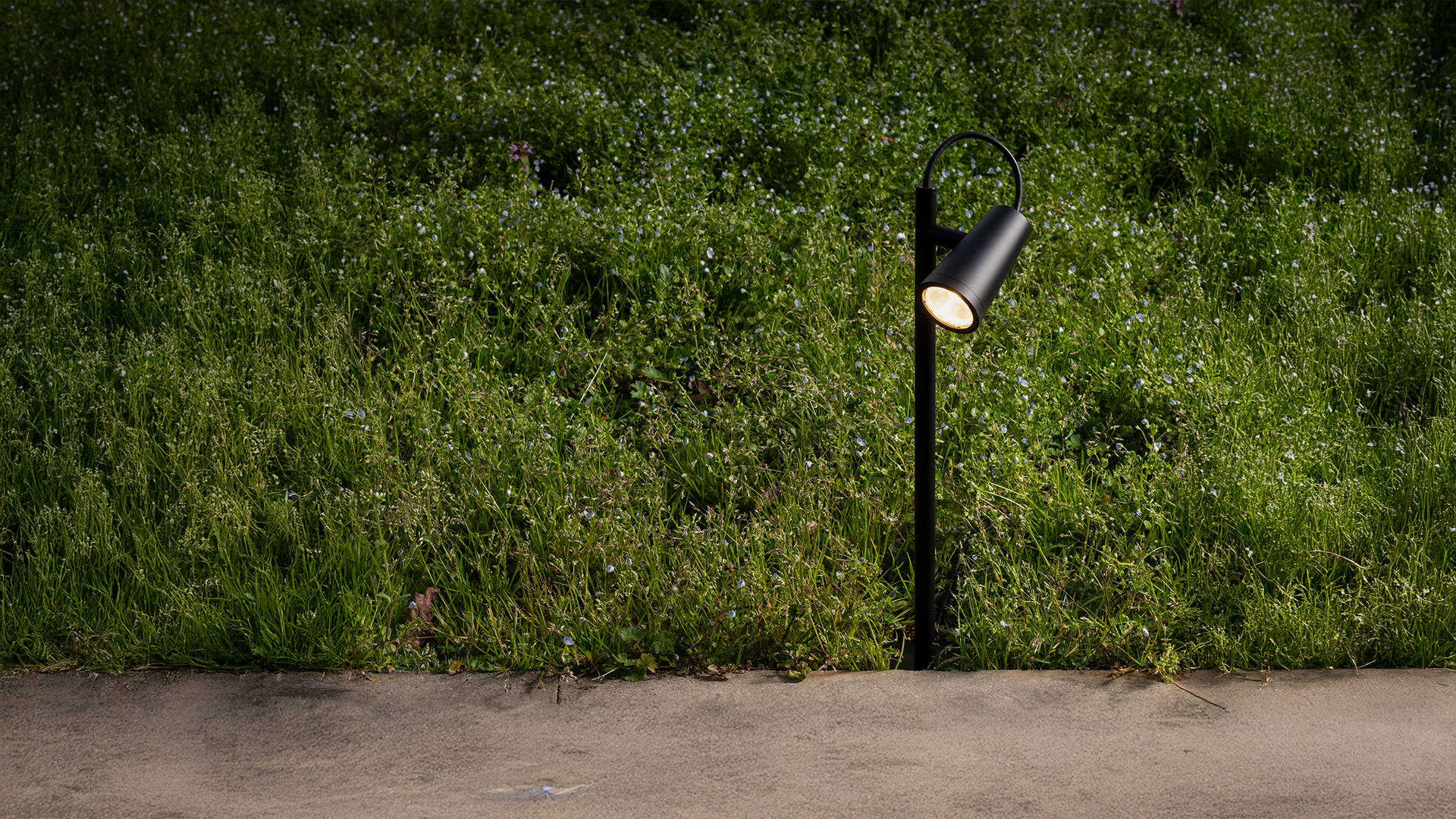 Artemide Conus outdoor pole lamp with two conical dark gray spotlights mounted on a slim post, illuminated at night