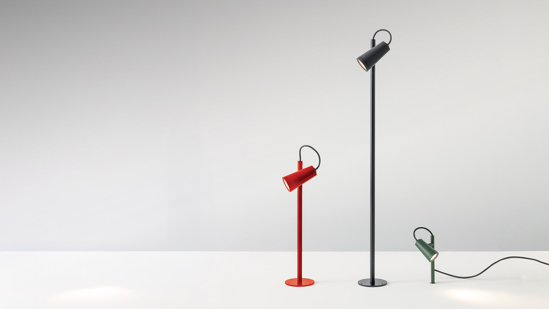 Artemide Conus floor lamp: dark metal stem with circular LED head emitting warm ring light, elegant curved cable detail