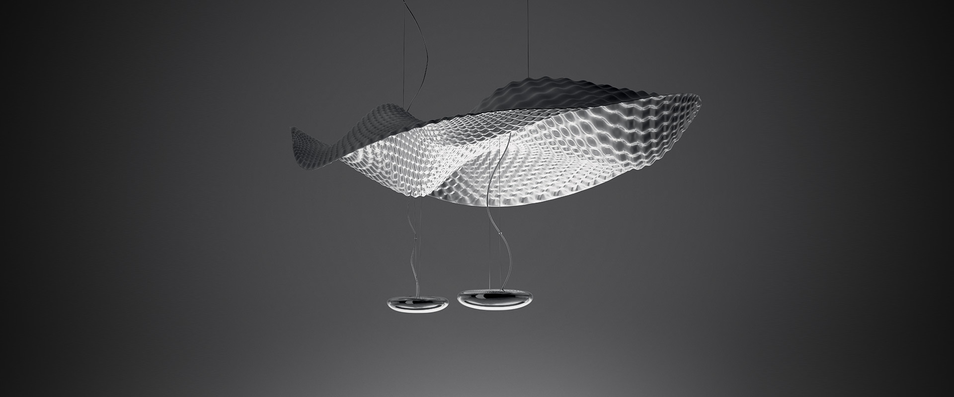 Modern office lounge with Artemide Cosmic Angel pendant lamps featuring decorative mesh diffusers, illuminating seating areas with round tables