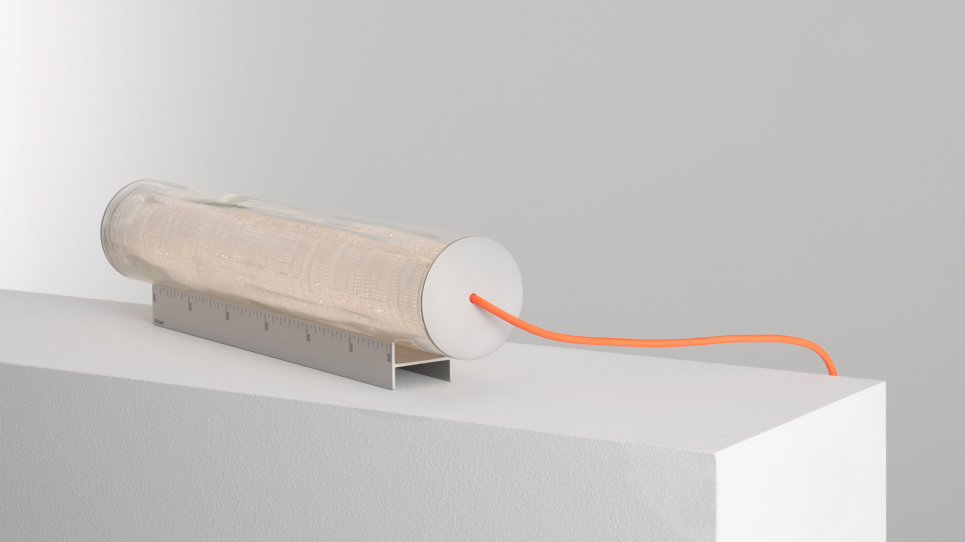 Artemide Criosfera pendant tube lights suspended from an industrial ceiling with metal cable trays and red pipes.