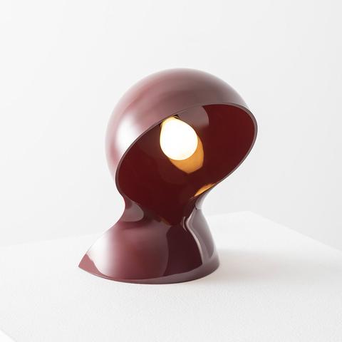 Artemide Dalù table lamp in burgundy red, sculptural rounded shell shape tilted to reveal a warm glowing bulb inside