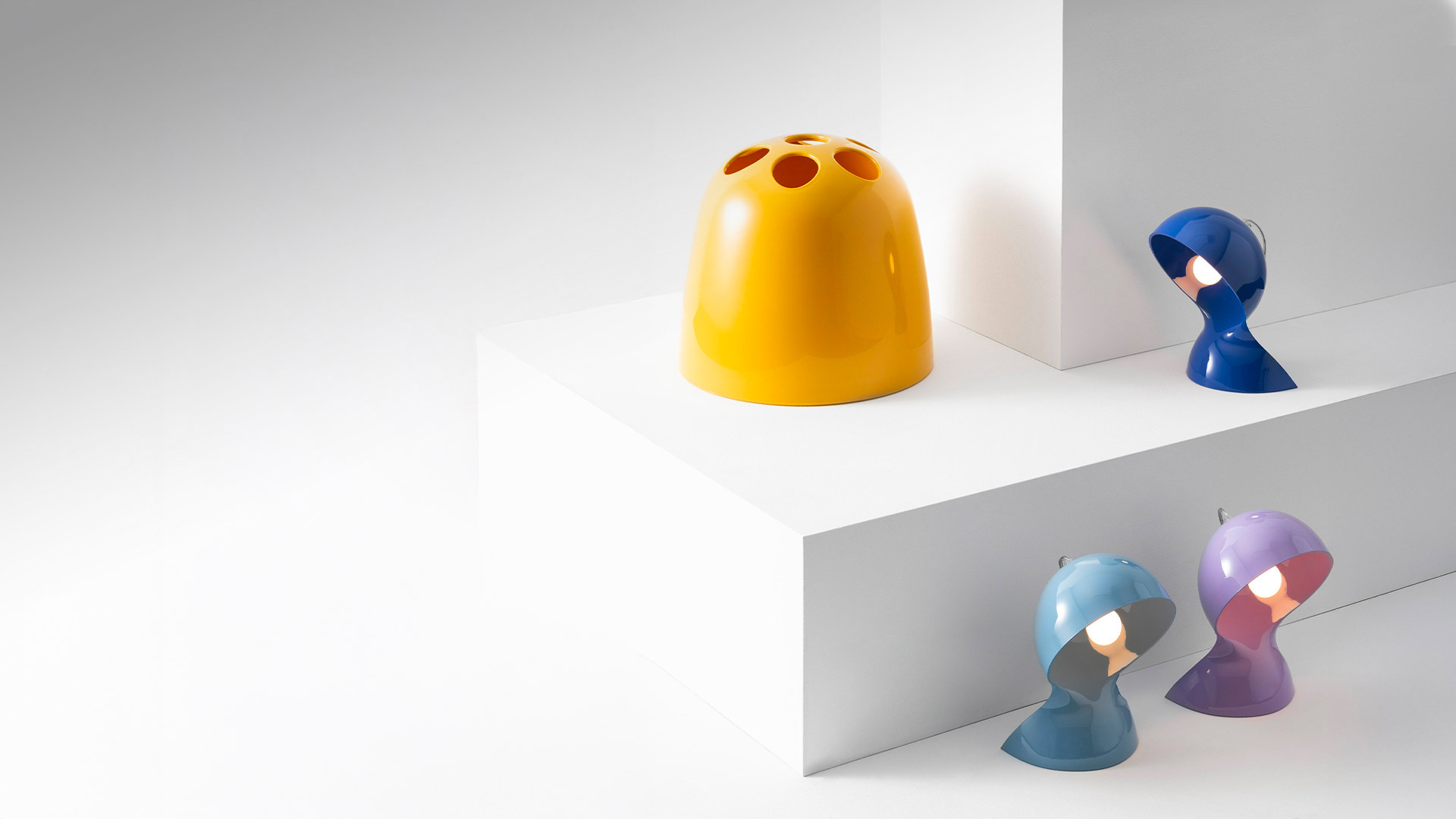 Artemide Dalù table lamps in yellow, blue, light blue, and purple, featuring a rounded dome shape with a circular opening for directional light