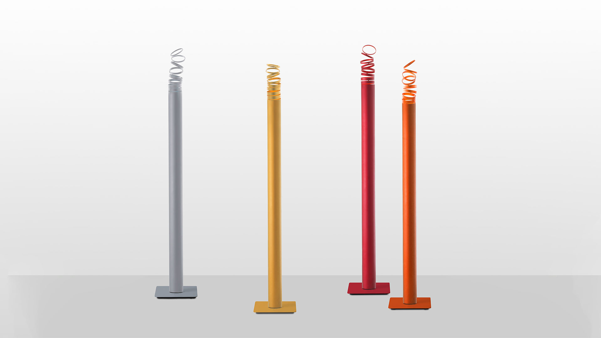 Four Artemide Decomposé Light Terra floor lamps with slim poles and spiral LED tops in grey, yellow, red, and orange
