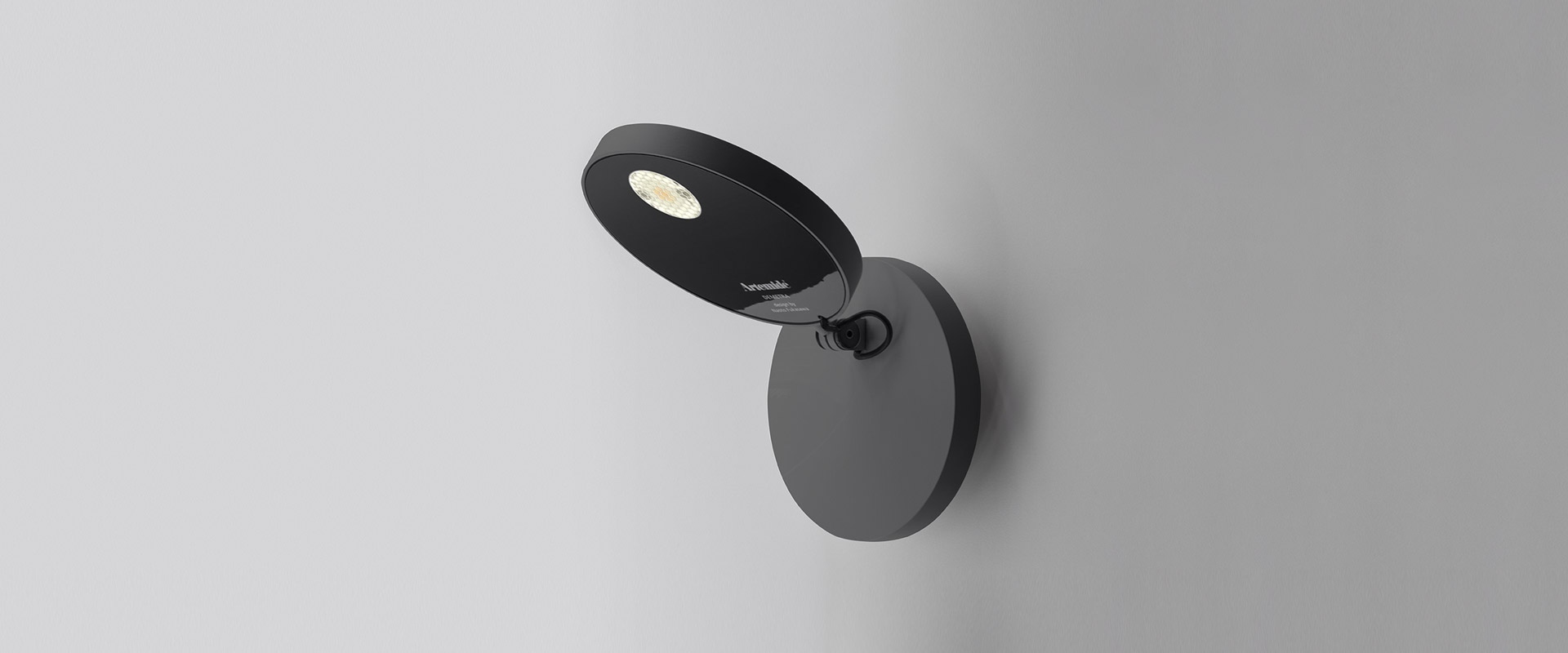 Artemide Demetra Faretto wall spotlight in matte black, featuring an adjustable oval head with integrated LED, mounted on a round base