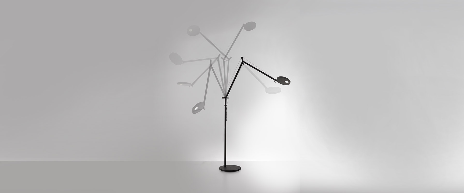 Artemide Demetra Reading Floor lamp with slim arched stem beside a cream bouclé sofa in a teal-panelled living room