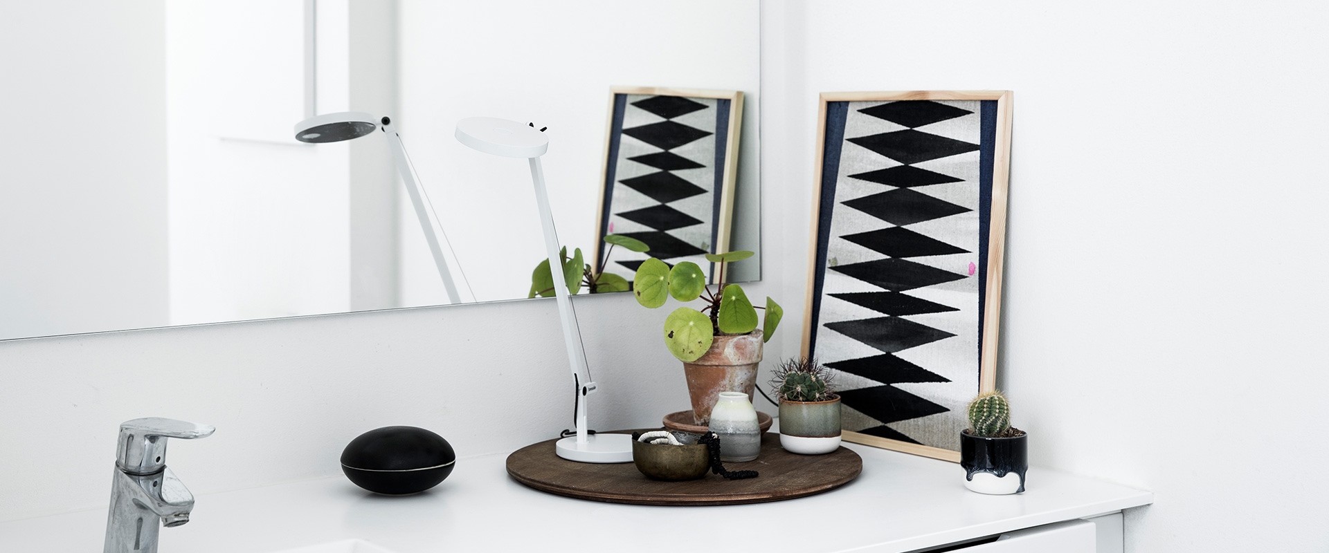 Artemide Demetra Micro table lamp in black, featuring an adjustable arm, circular LED head, and round base with black cord.