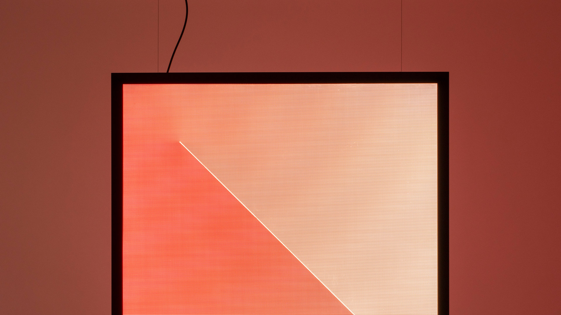 Artemide Discovery Dialogue square LED panel emitting a diagonal gradient light from green to warm peach, mounted on olive wall
