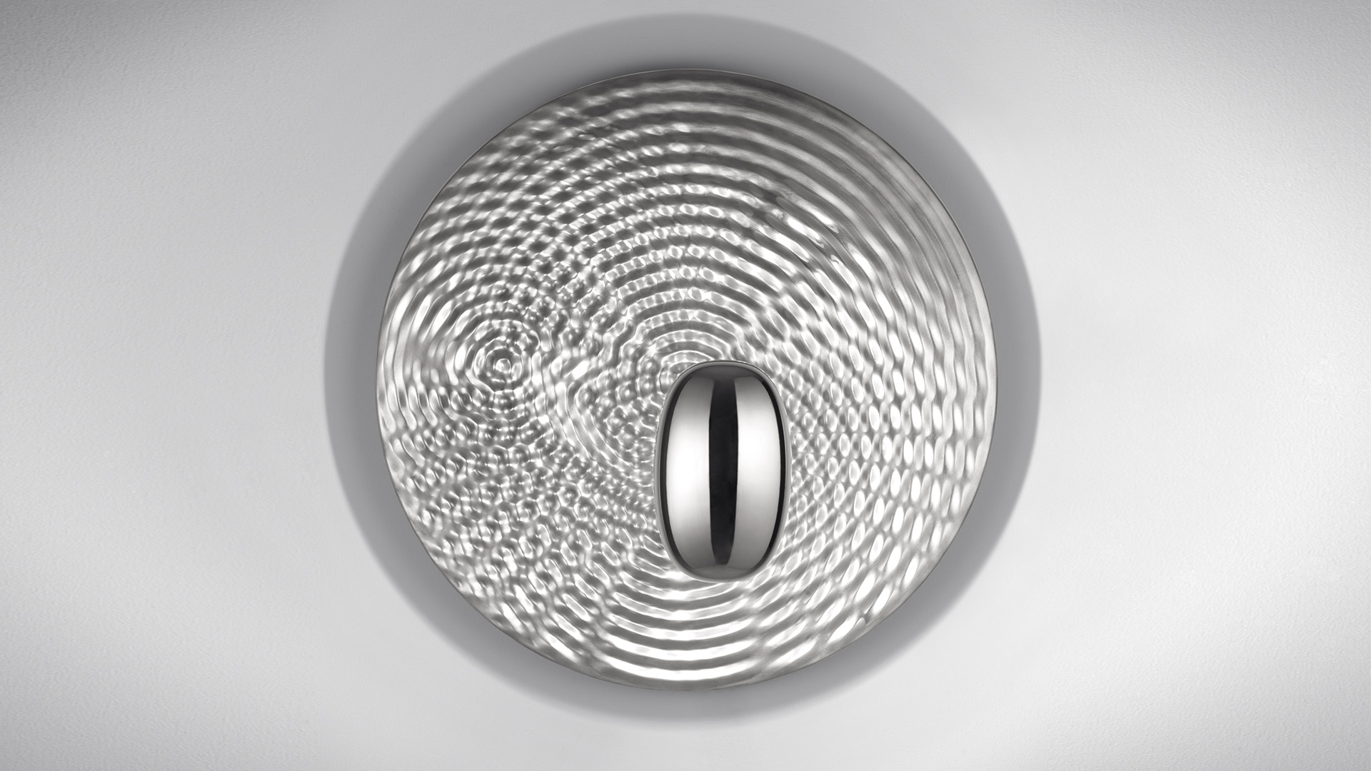 Artemide Droplet ceiling lamp, top view: circular diffuser with concentric wave patterns in silver, oval central LED element